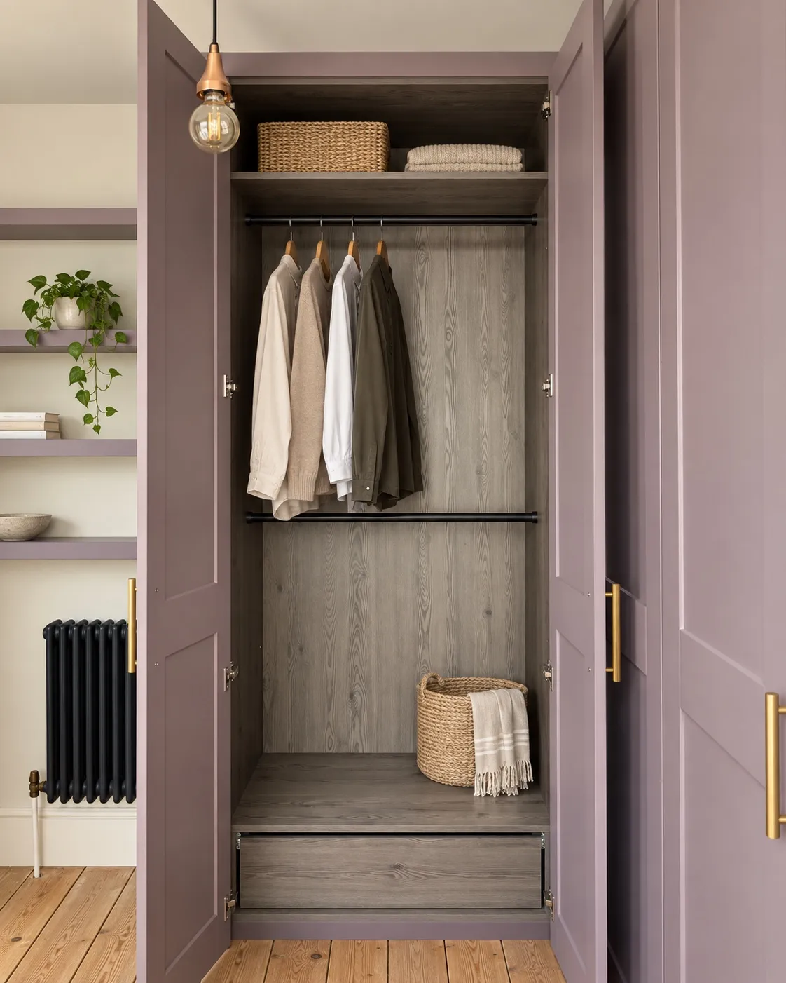An open wardrobe in a purple dressing room, with hanging rails and a drawer inside