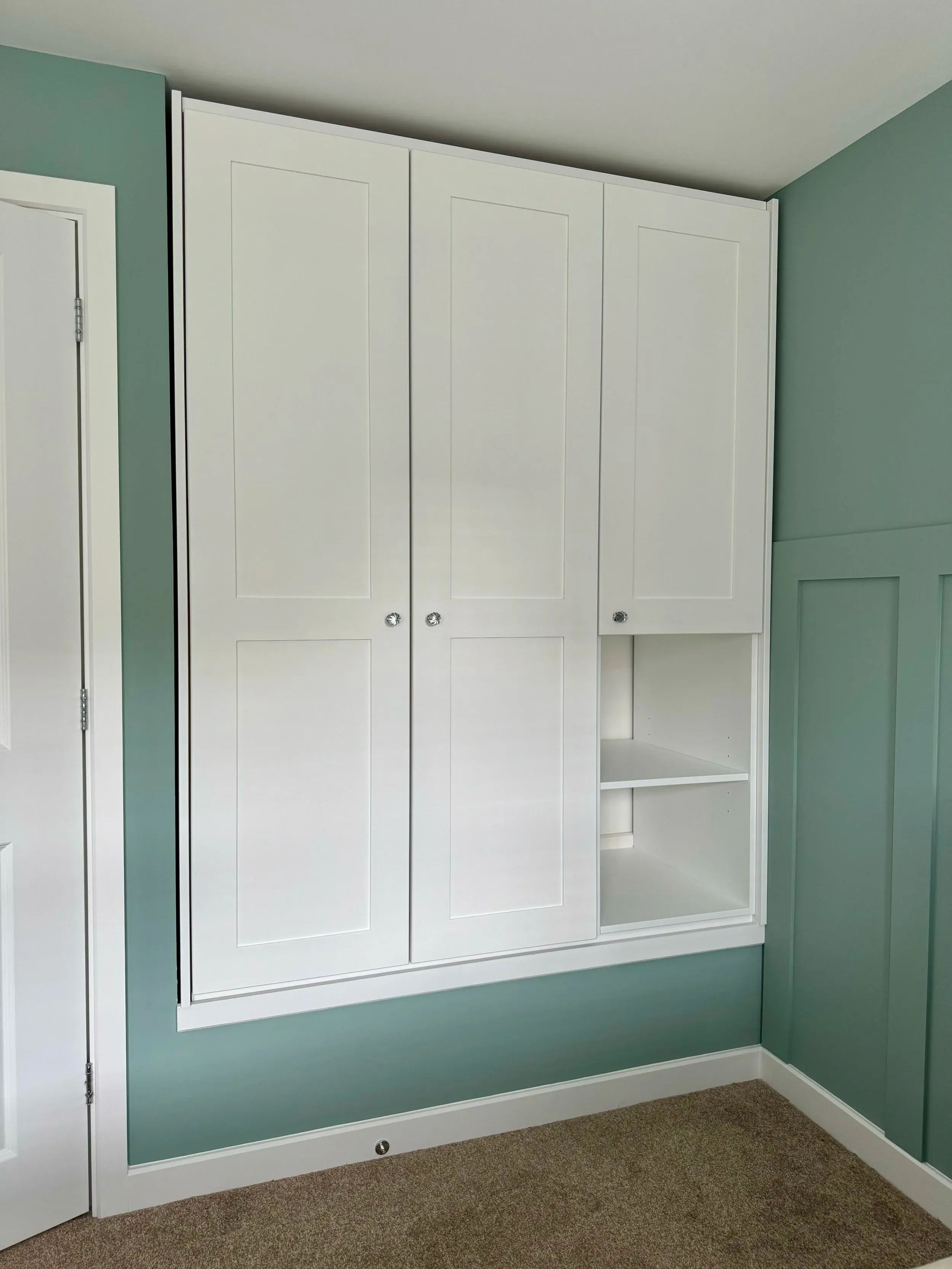 White fitted wardrobes against a green wall